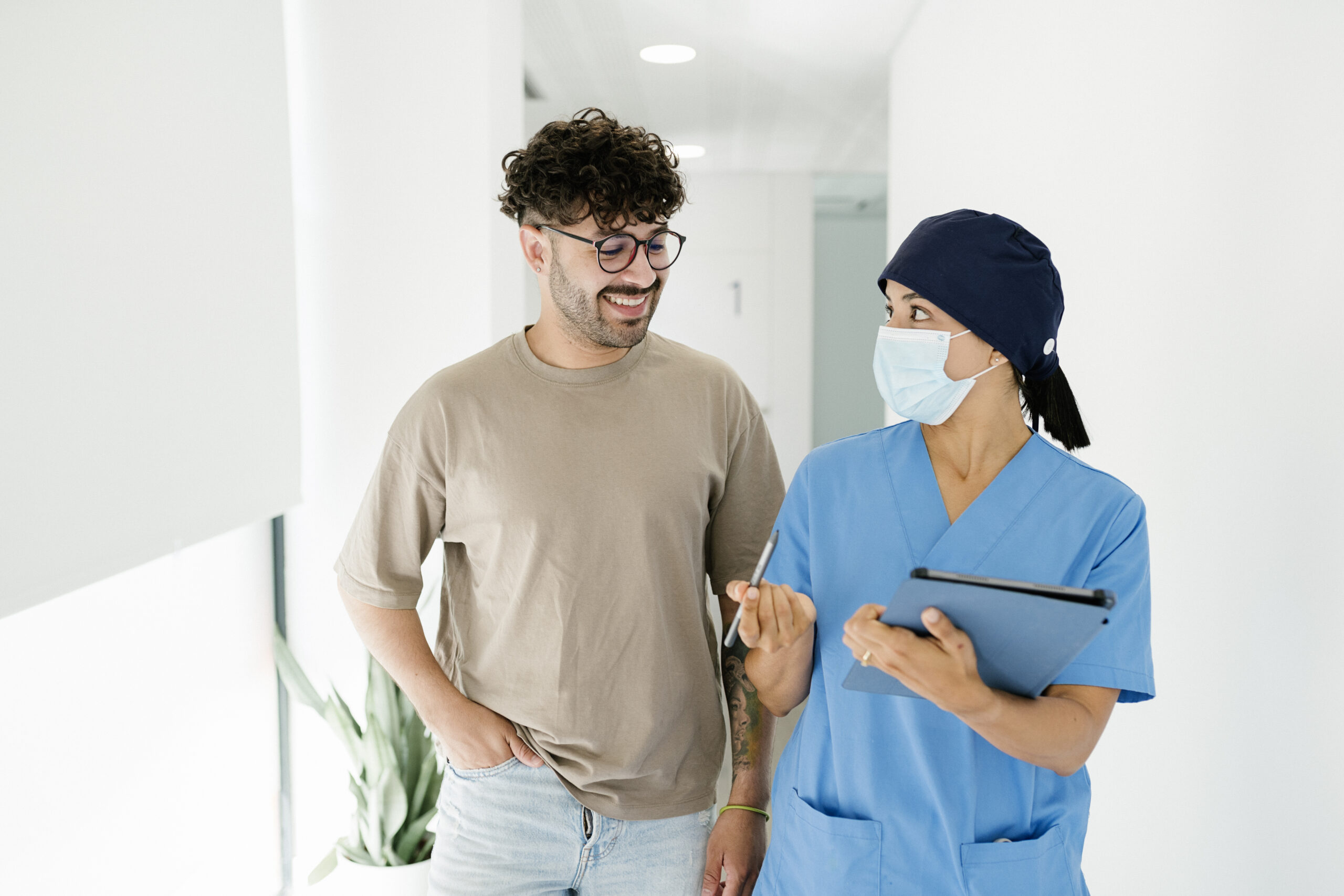 nurse wearing surgical mask explaining medical procedure to patient in clinic