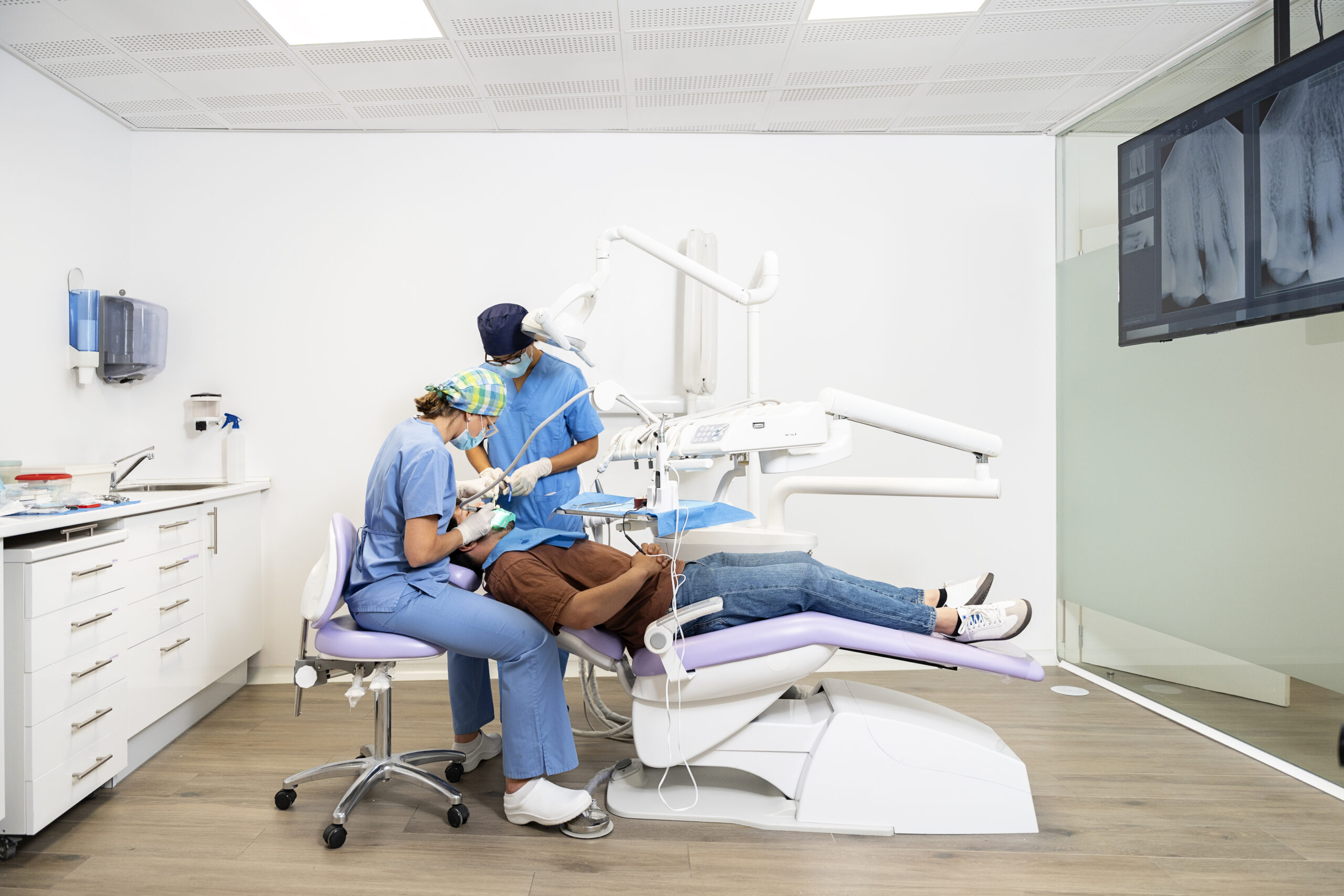 dentist and assistant performing dental check up on patient