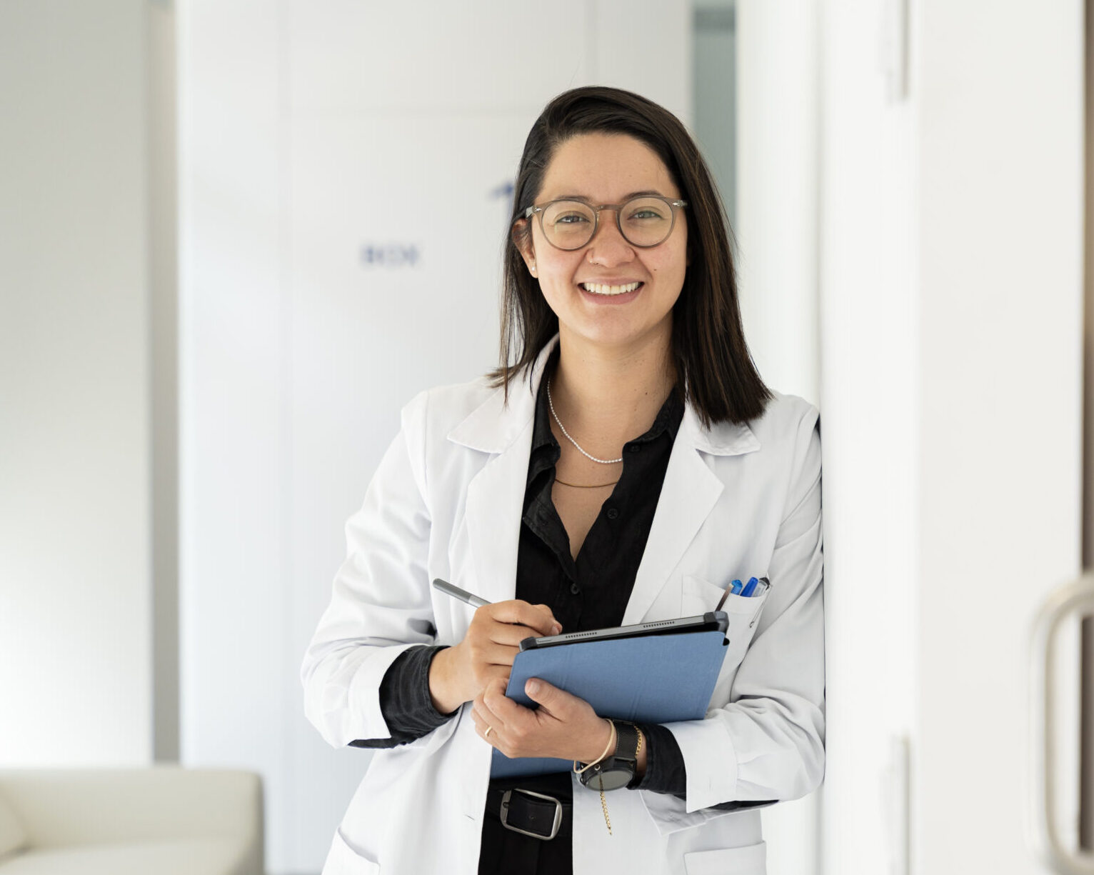 female doctor smiling and taking notes on a clipboard in a medical clinic